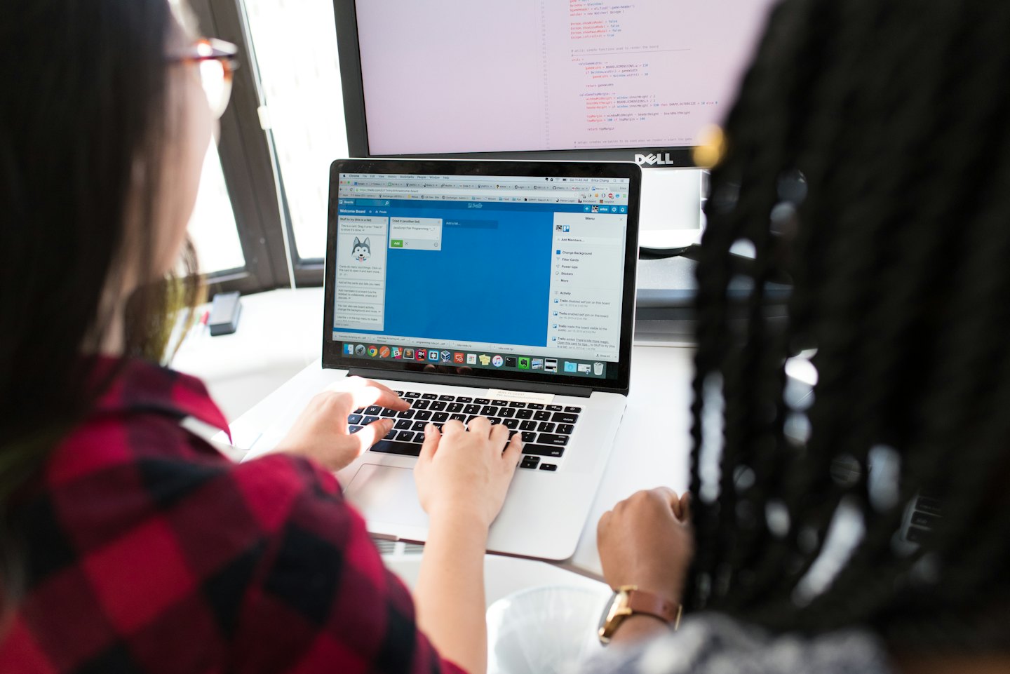 Two colleagues working together on a laptop with Trello.